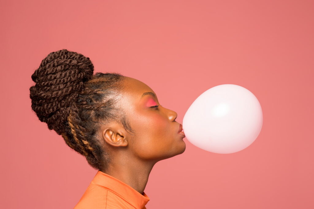 Femme faisant une bulle avec un chewimg gum.